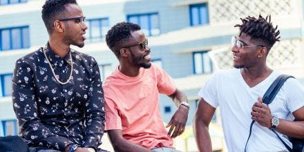 A group of three fashionable African American students communicating on the street